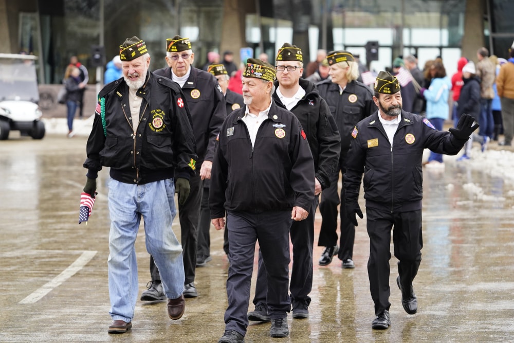 Group of Veterans walking in a parade and waving at their onlookers.