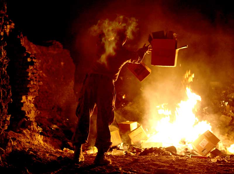 person throws boxes into burn pit