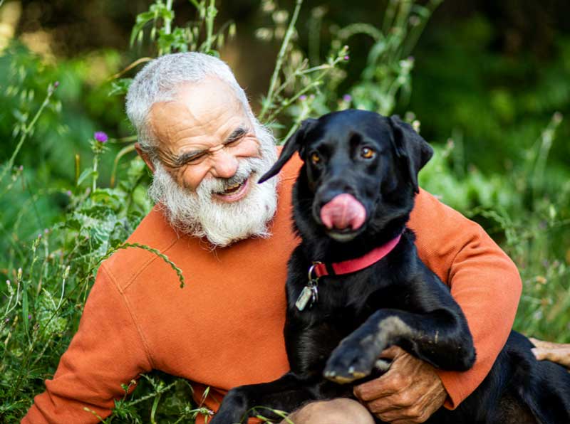 Veteran in field laughs with dog