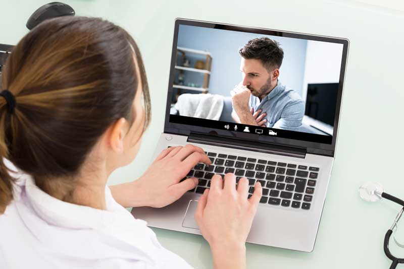 A doctor meets with a Veteran for a telemedicine appointment on her laptop. doctor meets with veteran via laptop
