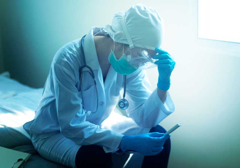 A doctor takes a moment to sit down and check their telehealth messages on their phone. doctor, sitting, checks phone