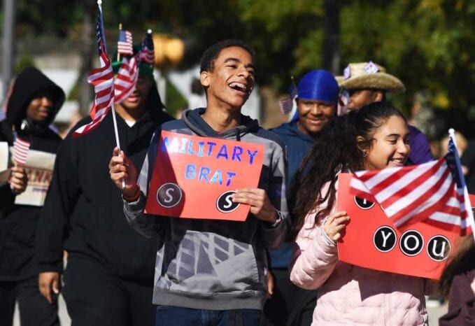 A small group of onlookers positively cheers on Veterans in a parade setting