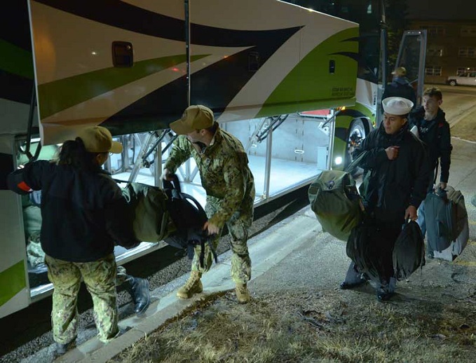 Navy service members load gear on bus