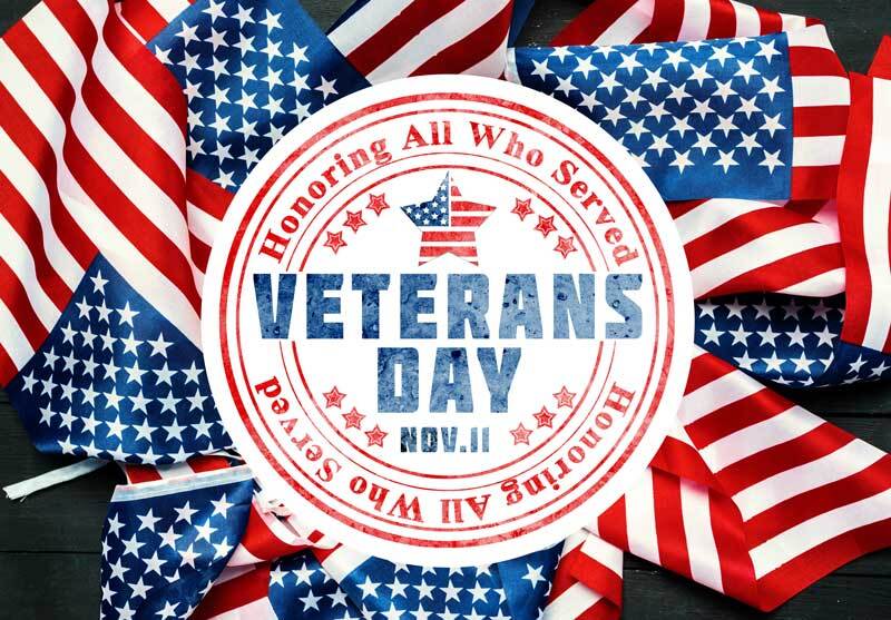 A Veterans Day sign honoring all who served surrounded by American flags Veterans Day sign with American flags