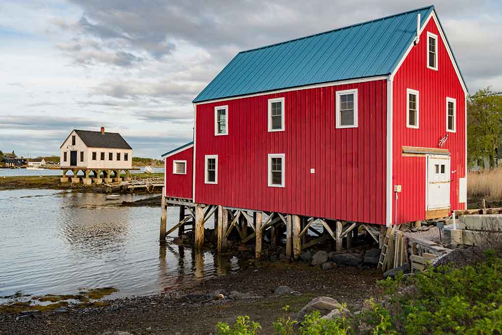 Maine coastal red building on stilts.