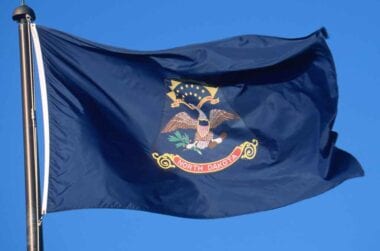 North Dakota state flag waving in a blue sky.