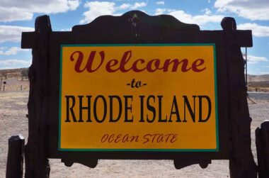 Welcome to Rhode Island yellow wooden road sign.