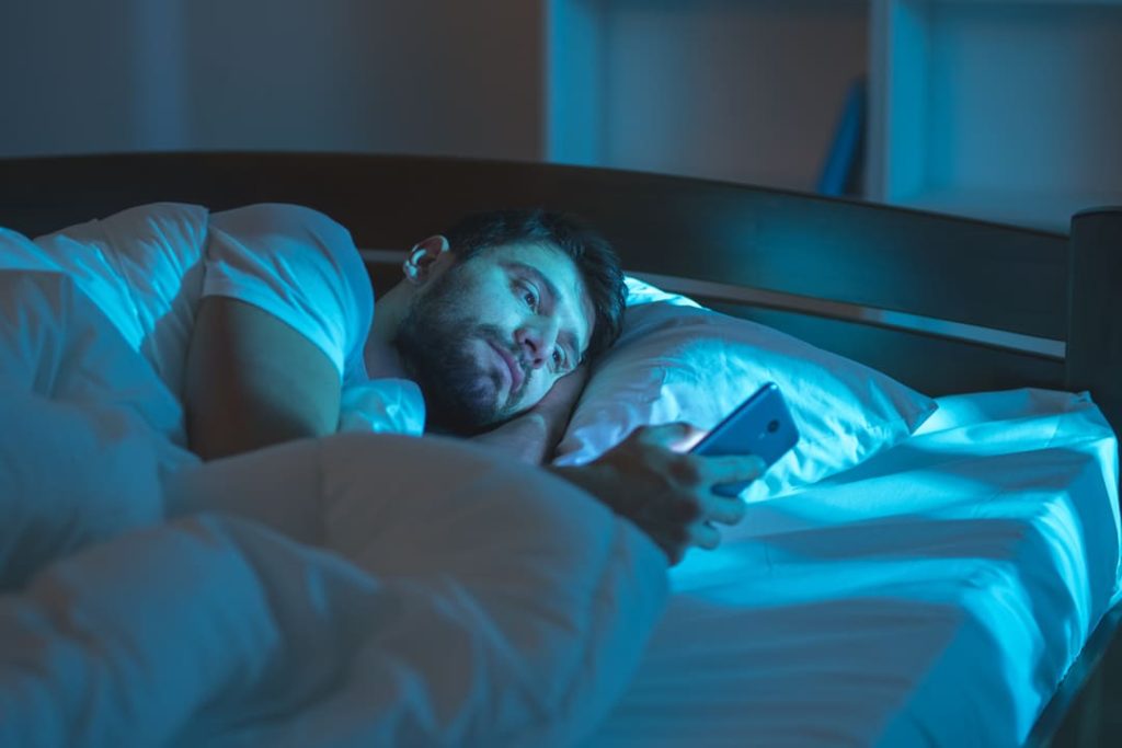 veteran looking at phone awake in bed