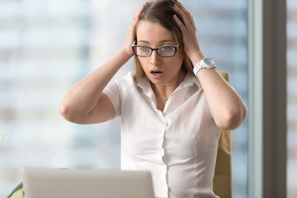 Woman in glasses with hands on head in disbelief.