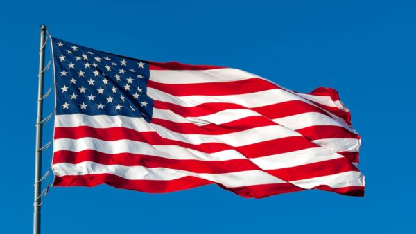 AMERICAN FLAG FLYING IN CLEAR BLUE SKY.