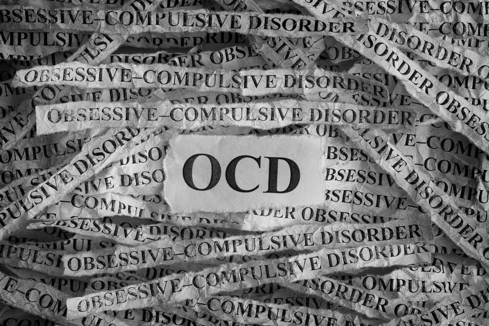 OCD sign with shredded paper typed with "obsessive-compulsive disorder" all around it.