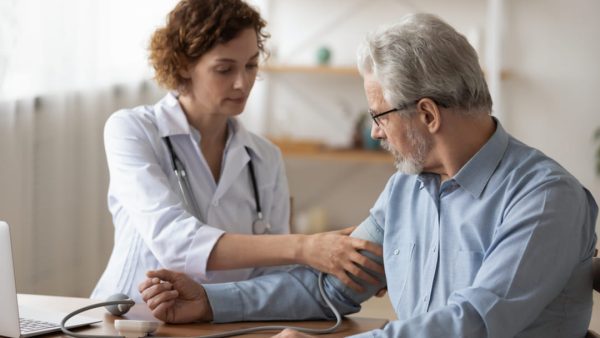 WOMAN DOCTOR CHECKING MANS BLOOD PRESSURE.