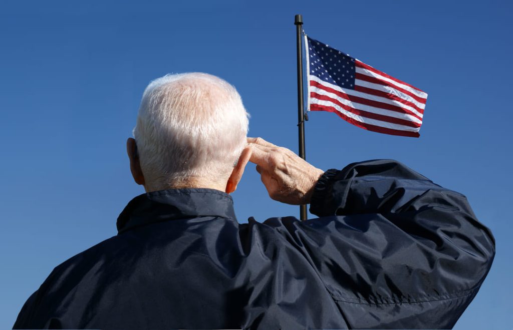 US veteran saluting a US flag.