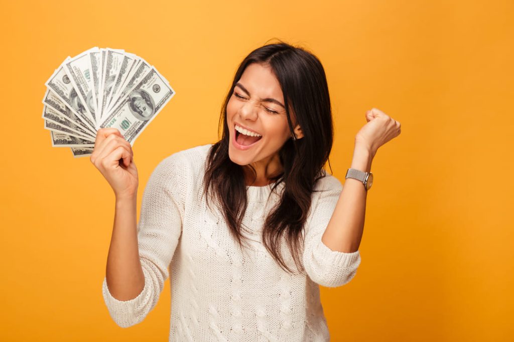 Girl excited holding cash yellow backdrop.