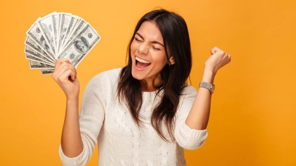 Girl excited holding cash yellow backdrop.